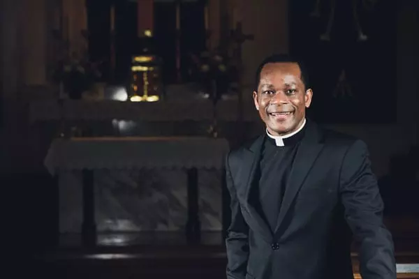 A man in black suit standing next to a church.