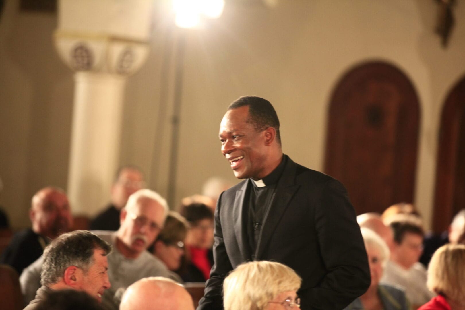 A man in black jacket standing next to crowd.