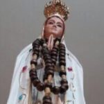 A statue of the virgin mary with rosary beads.