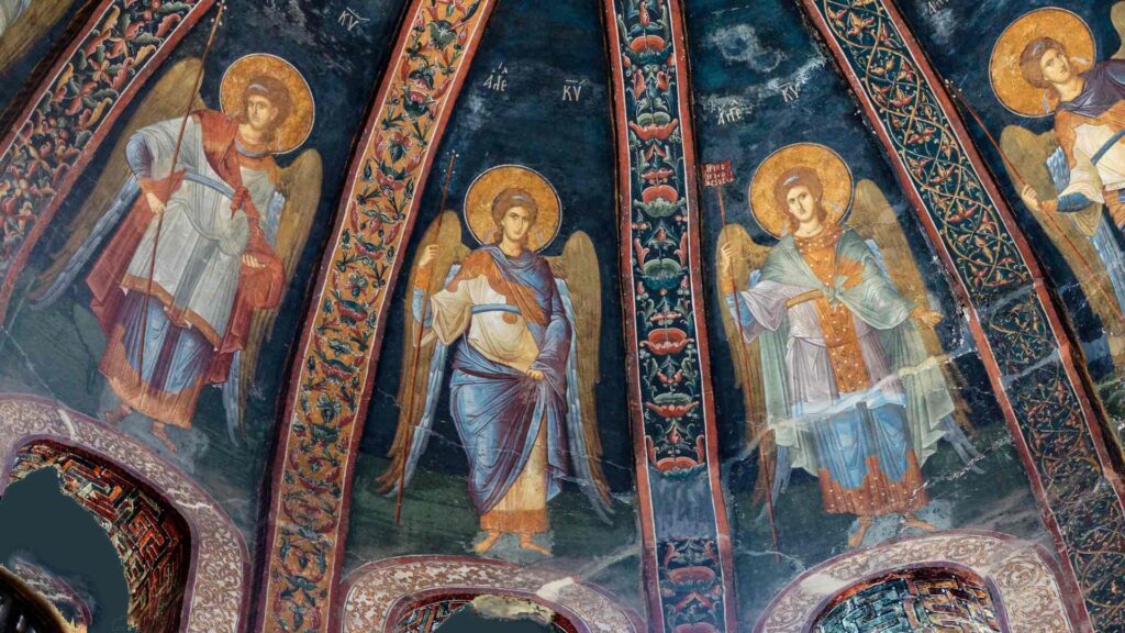 A painting of angels in the ceiling of an old church.