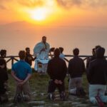 A group of people sitting on top of a hill.