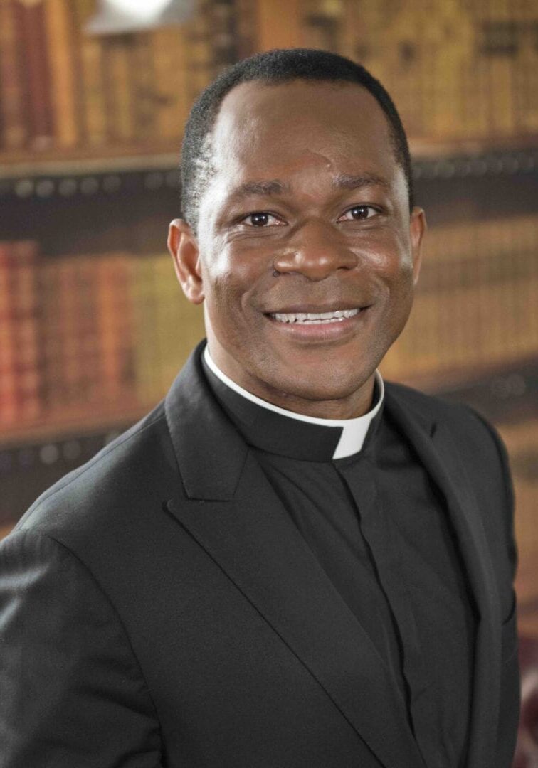 A man in black suit and white shirt smiling.