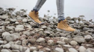 A person wearing boots and jeans on top of rocks.